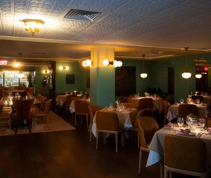 Wide view of the Parlor at Rockwell & Rose – sage paneling, soft lighting, and tables dressed for dinner service.
