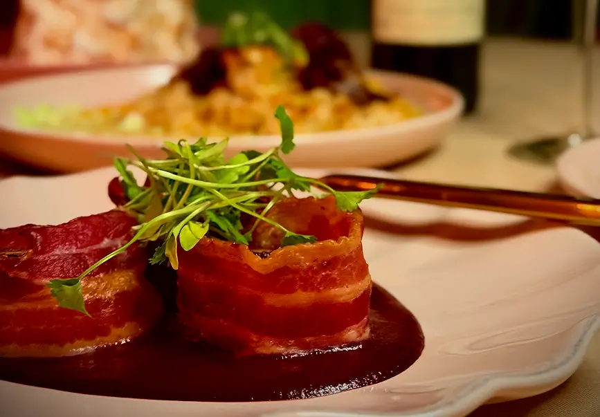 Center Cut Filet wrapped in crisp bacon, finished with maître d’ butter sauce and microgreens – served with “Elote slaw” and wilted spinach.