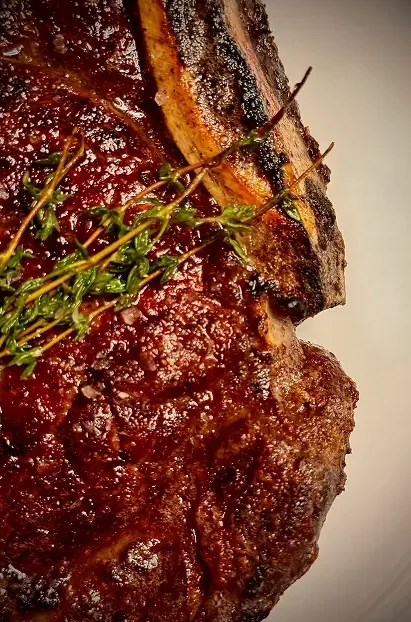 Close-up of Rockwell & Rose’s dry-aged bone-in ribeye, finished with charred rosemary and coarse sea salt.